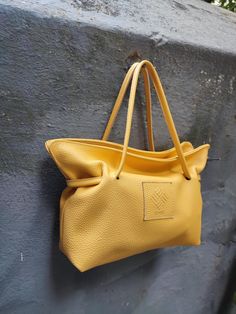 Corvo leather purse in yellow. A beautiful leather shoulder bag that can also be used as a crossbody, perfect for everyday use. It complements any outfit, from casual to formal, making it ideal for business meetings and special occasions. This bag will become your go-to accessory for every look! This handmade purse, crafted by local artisans in our studio, is made from genuine Italian cow leather and features a soft cotton lining with leather details. Inside, there's a small leather pocket, and it closes with a magnetic snap for convenience. The bag includes two straps: a short leather strap and a long adjustable strap made from a combination of leather and fabric. All hardware parts are in silver. Dimensions: Length 33 cm (13 in), Height 20 cm (7,9 in), Depth 10 cm (3,95 in). We ship all Shopping Shoulder Bag With Rolled Handles, Everyday Bags With Rolled Handles And Pouch Shape, Everyday Pouch Shoulder Bag With Rolled Handles, Everyday Pouch Bag With Rolled Handles, Yellow Top Handle Bucket Bag For Travel, Beach Shoulder Bag With Rolled Handles, Mustard Satchel Shoulder Bag For Everyday, Everyday Use Crossbody Satchel With Rolled Handles, Everyday Crossbody Satchel With Rolled Handles