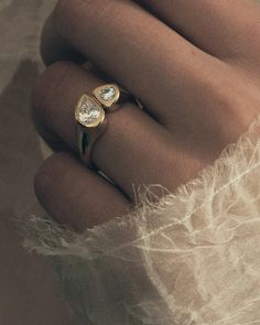 a woman's hand with two gold rings on top of her finger and the other one has a diamond in it