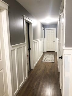 an empty hallway with wood floors and white trim on the walls is seen in this image