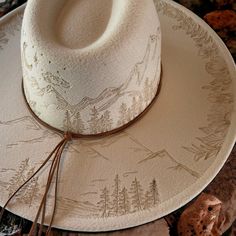 Wide Brim Hat in Light Taupe Burned Hat using Pyrography Techniques. All art is applied freehanded. Each Hat is a One of a Kind. Each Hat made by PIPER comes with a Macramé Wall Hat Hanger and Travel Bag. Hats are sealed for weather and wear. Mountain Burned Hat, Aztec Burned Hat, Trending Hats For Women, Sunflower Burned Hat, Hat Looks For Women, Felt Hat Burning Designs, Hat Burning Ideas, Custom Cowgirl Hats, Hat Customization