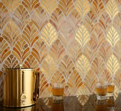 two cups on a table in front of a wallpapered background with gold leaves