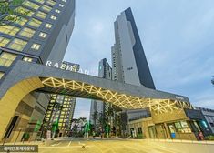 the entrance to an office building with lights on it's sides and tall buildings in the background