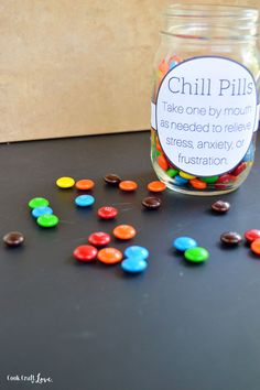 a jar filled with colorful candies sitting on top of a black table next to a sign