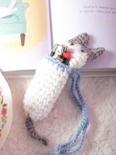 there is a crocheted animal with a lighter in it's mouth next to a book