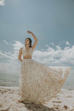 a woman standing on top of a beach next to the ocean wearing a white dress