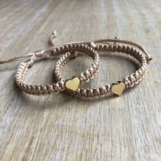 two bracelets with gold hearts are sitting on a table