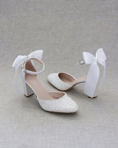 a pair of white shoes with bows on the toes and heels are sitting next to each other