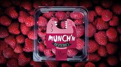 a plastic container filled with raspberries and the words munch n on it