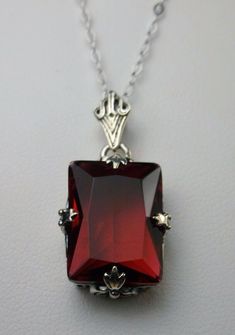 Simulated Red Ruby Pendant Description GL Design#15 Custom-Made This is a brand new stunning Art Deco style sterling silver filigree 10ct Simulated/man-made red ruby pendant necklace. The beautiful rectangle-cut ruby gem is 16mm in length 12mm in width. The 1.5mm necklace chain is 18 inches in length. The entire pendant is 1 1/8th inches long by 9/16th inches wide. Notice the beautiful craftsmanship of the silver Deco filigree bail. This is a lovely new, well made/sturdy, pendant and necklace it Vintage Art Deco Necklace, Leaf Filigree, Red Pendant Necklace, Ruby Necklace Pendant, Rectangle Pendant, Red Pendants, Ruby Pendant, Necklace Design, Art Deco Necklace