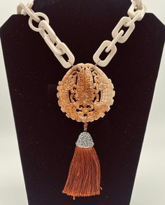 Spectacular necklace of resin links in bone color - two different shapes from Thailand .  Hanging from this beautiful necklace is a round and large Chinese carved Jade pendant in richly hand carved with intricate details, in warm caramel / brown. A silk copper color tassel with black rhinestones top hangs from pendant  Mesures: 23 inches long  Brass Clasp Pendant is app 2 1/2  A note from the designer, SophiaI design and handcraft my jewelry at my studio in Florida. You can rest assured that no Luxury Brown Hand-strung Necklaces, Asian Necklace, Beaded Jewelry Necklaces, Rhinestone Top, Earth Tone Colors, Carved Jade, Bone Color, Caramel Brown, Jade Carving