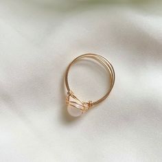 a gold ring with a pearl on it sitting on top of a white cloth covered surface