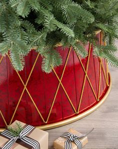 a christmas tree in a red pot with presents under it and a ribbon tied around the top