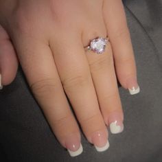 a woman's manicured nails and ring with a heart shaped diamond on it