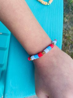 a child's arm with two bracelets on it and one is wearing a red, white, and blue beaded bracelet