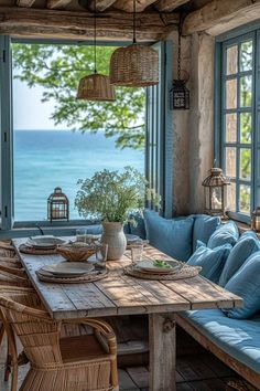 an outdoor dining area with blue cushions and wicker furniture, overlooking the ocean from a stone house