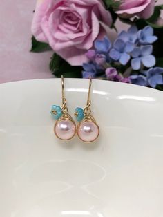 These one of a kind flowering beauties feature soft, blush pink Swarovski Crystal pearls that are meticulously wrapped in your choice of metal. The braided detailing looks amazing with these pearls. Accented with gold-dusted, aqua Czech glass flowers and gracefully suspended from handcrafted French ear wires. These are perfect for gift-giving or for yourself! - All components are 14kt yellow gold filled, 14kt rose gold filled or sterling silver depending upon your choice. - Swarovski Crystal pea Whimsical Pink Dangle Flower Earrings, Whimsical Pink Earrings With Flower Charm, Elegant Pink Petal-shaped Flower Earrings, Handmade Feminine Dangle Flower Earrings, Handmade Feminine Drop Flower Earrings, Handmade Feminine Drop Earrings, Rose Gold Flower Drop Earrings With Pearl, Rose Gold Pearl Drop Flower Earrings, Handmade Pink Teardrop Flower Earrings