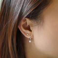 a close up of a woman's ear wearing gold earrings with pearls on them