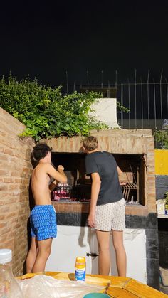 two people standing in front of an outdoor oven