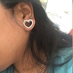 a woman wearing an earring with a heart shaped object on it's side