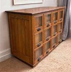 a wooden cabinet with glass doors on the bottom and sides, in front of a window