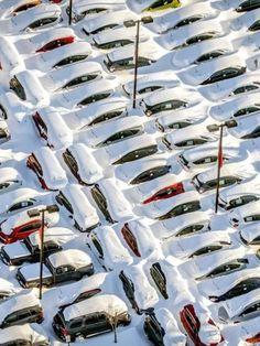 many cars are covered in snow and parked on the side of a road with poles sticking out of them