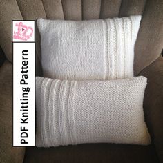 two white knitted pillows sitting on top of a brown chair