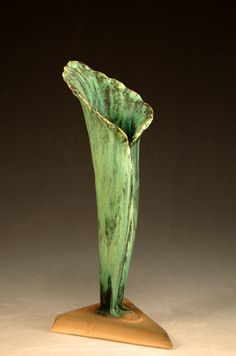 a green vase sitting on top of a wooden stand