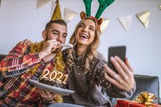 a man and woman sitting next to each other in front of a christmas cake with antlers on it