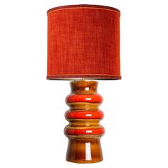 an orange lamp with a red shade on it's side and a white background