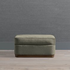 a small footstool sitting on top of a wooden floor next to a gray wall