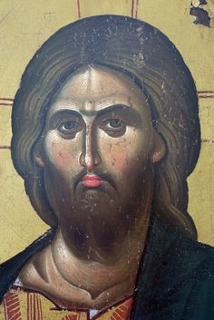 an old painting of jesus on the side of a yellow wall with red and black stripes