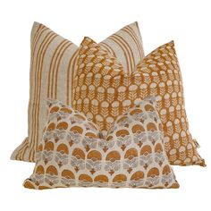 three decorative pillows with orange and white designs