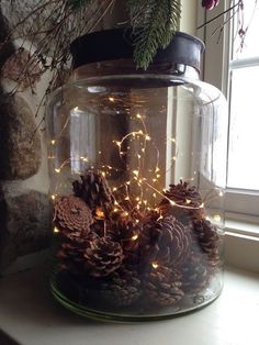 a glass jar filled with pine cones and lights