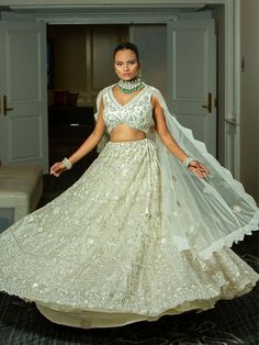 This ivory bridal lehenga set exudes elegance with intricate silver embroidery on a sleeveless blouse, a flowing lehenga skirt, and a sheer, delicately embroidered dupatta. Perfect for brides seeking a timeless and graceful look. Key Features: Color: Chiffron Off-White Components: Sleeveless blouse, full lehenga skirt, and sheer embroidered dupatta Design: Floral and geometric embroidery covering the entire set Dupatta: Sheer with embroidered edges for an elegant drape Occasion: Perfect for wedd Ivory Bridal Lehenga, Buy Lehenga Online, Indian Bridal Couture, Elegant Veils, Dupatta Design, Reception Gowns, Mehendi Outfits, Bridal Lehenga Red, Green Lehenga