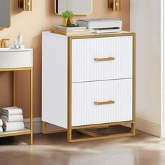 a white and gold cabinet with two drawers next to a mirror on the wall in a bathroom