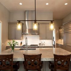 a large kitchen island with four chairs and lights hanging from it's ceiling over the counter