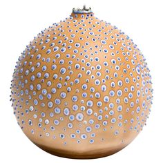 a brown vase with blue dots on the top and bottom, sitting in front of a white background