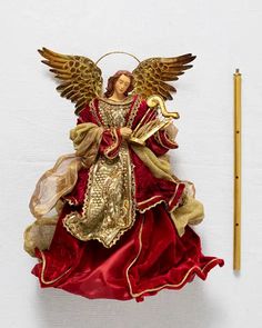 an angel figurine sitting on top of a red cloth next to a pencil