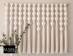 a white wall hanging with tassels on it and a vase filled with flowers