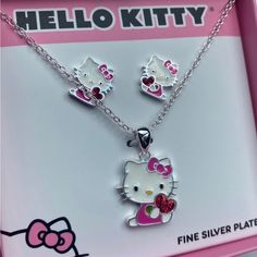 Hello Kitty Jewelry Set Seated Hello Kitty Clutching A Ruby Red Heart Matching Earrings Included! Pendant And Chain Are Crafted From Silver-Plated Brass. Hello Kitty Necklace Features A Delightful Pendant Adorned With Enamel Plating In A Spectrum Of Vibrant Shades, Complemented By A Glimmering Crystal Accent. Approx. 16” Length Cute Silver Jewelry For Mother's Day, Cute Silver Heart Shaped Jewelry, Cute Heart Shaped Silver Jewelry, Cute Silver Heart Jewelry, Cute Sterling Silver Jewelry For Valentine's Day, Playful Silver Jewelry For Mother's Day, Cute Silver Heart-shaped Jewelry, Pink Sterling Silver Jewelry Sets As Gift, Playful Handmade Silver Jewelry