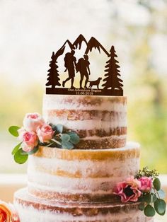 a wedding cake with the silhouette of two people and a dog on top is decorated with flowers