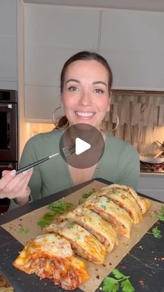 a woman is holding a tray with pizza on it and she has a knife in her hand