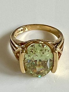 "Stunning 925 gold-plated size 7 ring with magnificent oval light green gemstone. The gold-plating is high polished and smooth. The green gemstone is catches the light and sparkles. The gemstone approximately measures 9/16\" in length and 6/16\" (1/2\")  in width.  Love the unusual setting. The ring is in excellent condition and is stamped UTC 925. Total weight 6.42 grams. https://bettyjosboutique.etsy.com" Green Topaz Ring For Formal Occasions, Formal Green Topaz Ring, Luxury Green Topaz Gemstone Ring, Luxury Gold Oval Emerald Ring, Formal Green Ring With Large Stone, Elegant Green Oval Topaz Ring, Gold Round Gemstones With Large Stone, Green Oval Stone Setting Rings, Gold Ring With Large Oval Cabochon Stone