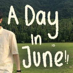 a man standing on top of a lush green field next to a tree covered hillside