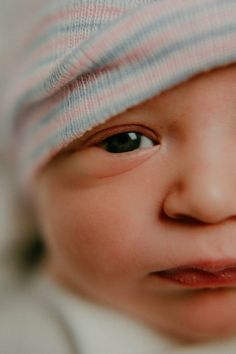 a close up of a baby's face with a hat on top of it