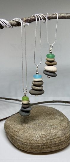 We've paired our popular Cairn pendant with summery beach glass to create one of a kind statement pieces! Each pendant is truly unique; although each pendant's smooth glass and rocks are similar in size, the colors of each will vary and each is beautiful in its own way.  I take care in selecting the placement of each stone in the stack. The pendant is made with smooth lake stones (sourced in Ohio), beach glass, and are chased with plated silver wire.  A complimentary 24" plated silver necklace i Diy Rock Jewelry, Cairn Necklace, Jewelry Making Pearls, Rock Pendant, Beach Stones Jewelry, Pebble Jewelry, Necklace Minimalist Jewelry, Rock Necklace, Art Jewelry Contemporary