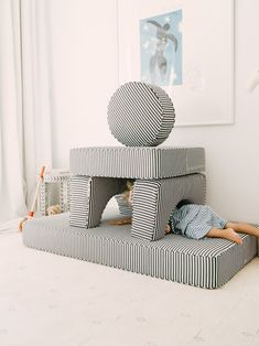 a young child laying on top of a bed made out of cardboard blocks in a white room