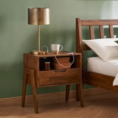 a nightstand with a lamp on it next to a bed