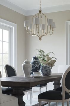 a dining room table with chairs and vases on it