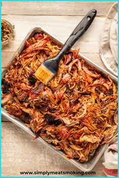 a pan filled with shredded meat and a spatula on top of the tray next to it